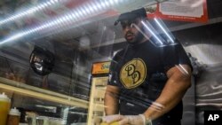 Alex Batista, co-owner of Deli-licious delicatessen in the Queens borough of New York, April 6, 2020, makes a sandwich at the store.