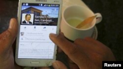 A person uses a smartphone to look at the Facebook page of Cambodia's Prime Minister Hun Sen, during breakfast at a restaurant in central Phnom Penh. A recent newspaper report questioned whether the prime minister bought "likes" for his page.