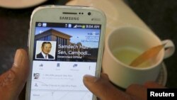 A person uses a smartphone to look at the Facebook page of Cambodia's Prime Minister Hun Sen, during breakfast at a restaurant in central Phnom Penh, Cambodia.