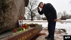 A man bows after leaving flowers at a monument to the victims of political repression in memory of late opposition leader Boris Nemtsov in Saint Petersburg, Russia, on the 10th anniversary of Nemtsov's assassination, Feb. 27, 2025.