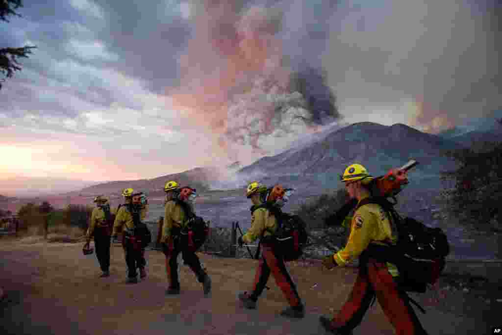 Firefighters walk in line during a wildfire in Yucaipa, California.&#160;Three fast-spreading wildfires sent people fleeing with one trapping campers at a reservoir in the Sierra National Forest, as a brutal heat wave pushed temperatures into triple digits.