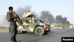 An Afghan police officer keeps watch near the site of a suicide car bomb blast in Kandahar, Afghanistan, July 18, 2019. 