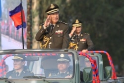 FILE - Cambodian Prime Minister Hun Sen (L) salutes, along with his son, Lt. Gen. Hun Manet (background) during an inspection of troops at a ceremony in Phnom Penh, Cambodia, Jan. 24, 2019. (Handout via AFP)