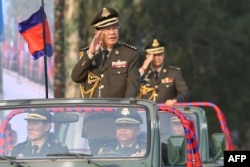 FILE - Cambodian Prime Minister Hun Sen (L) salutes, along with his son, Lt. Gen. Hun Manet (background) during an inspection of troops at a ceremony in Phnom Penh, Cambodia, Jan. 24, 2019. (Handout via AFP)