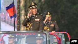 FILE - Cambodian Prime Minister Hun Sen (L) salutes, along with his son, Lt. Gen. Hun Manet (background), during an inspection of troops at a ceremony in Phnom Penh, Cambodia, Jan. 24, 2019. (Handout via AFP)