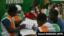 Des responsables de la commission électorale vérifient les listes électorales lors du décompte des votes dans un bureau de vote à Abidjan le 31 octobre 2020, après l'élection présidentielle ivoirienne.