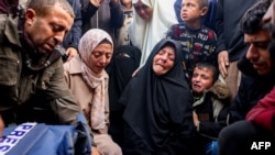 Family and relatives mourn over the body of Palestinian journalist Ahmed Al-Shayah, covered with a press vest, after he was killed during an Israeli strike the previous night in Khan Yunis, at Nasser Hospital, in the southern Gaza Strip, on January 16, 2025.