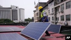 FILE— Oladapo Adekunle, an engineer with Rensource Energy, installs solar panels on a roof of a house in Lagos, Nigeria, March 21, 2024. 