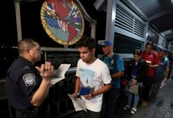 Cuban Abel Oset Jr., center, and his father Abel Oset, behind him, show their ID to a U.S. Customs and Border Protection officer before their appointments to apply for asylum in the U.S., as they leave Nuevo Laredo, Mexico, Sept. 17, 2019.