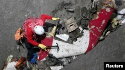 A French rescue worker inspects the remains of the Germanwings Airbus A320 at the site of the crash, near Seyne-les-Alpes, French Alps, March 29, 2015.