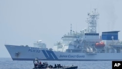 FILE - A Philippine Coast Guard rigid hull inflatable boat passes by the Japanese Coast Guard Akitsushima during a trilateral Coast Guard drill of the U.S., Japan and Philippines, near the waters of the disputed South China See in Bataan province, Philippines, June 6, 2023. 