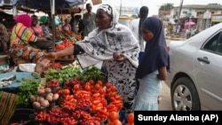 Idowu Bello, 56, buys onions to prepare a pot of soup at a market in Ibadan, Nigeria, Friday, Sept. 13, 2024.