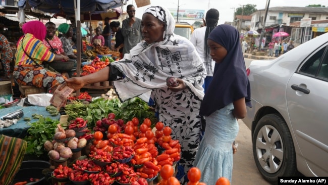 Idowu Bello, 56, buys onions to prepare a pot of soup at a market in Ibadan, Nigeria, Friday, Sept. 13, 2024.