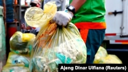 Seorang pekerja memegang kantong sampah medis untuk diangkut ke truk di Jakarta, 12 Agustus 2020. (Foto: Reuters/Ajeng Dinar Ulfiana)