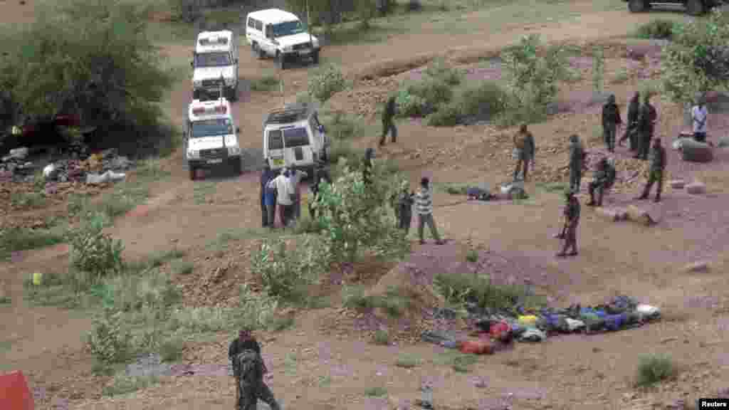 People stand near bodies lined up on the ground at a quarry site where attackers killed at least 36 workers in a village in Korome, outside the border town of Mandera, Dec. 2, 2014.