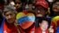 A woman holds a picture of Venezuela's President Hugo Chavez as supporters gather at Simon Bolivar square in Caracas,Venezuela, December 9, 2012.