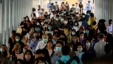 Commuters with facemasks to prevent the spread of the COVID-19 coronavirus walk to a train station at rush hour in Bangkok on August 20, 2020. (Photo by Mladen ANTONOV / AFP)