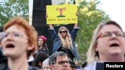 Image Description FILE - Abortion-rights campaigners attend a rally against new restrictions on abortion passed by legislatures in eight states including Georgia and Alabama, in New York City, May 21, 2019. 