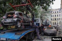 Pekerja mengeluarkan mobil yang rusak di lokasi yang dihantam rudal Rusia, di Lviv, Ukraina, 6 Juli 2023. (REUTERS/Roman Baluk)