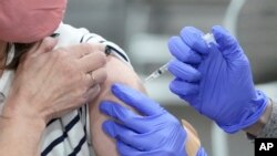  In this Wednesday, March 10, 2021 file photo, a woman receives a COVID-19 vaccination in Sandy, Utah.