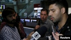 U.S. journalist Glenn Greenwald (C) looks on as his partner David Miranda (R) talks with the media after arriving at Rio de Janeiro's International Airport, August 19, 2013.