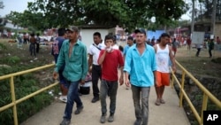 Men walk across a bridge inside the sports club where Central American migrants traveling with the annual Stations of the Cross caravan have been camped out, in Matias Romero, Oaxaca State, Mexico, April 4, 2018.