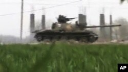 This image made from amateur video and released by Shaam News Network March 26, 2012, purports to show a Syrian military tank in Deir el-Zour, Syria. 