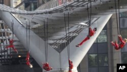 Extreme dancers perform, hanging from the Millennium Bridge in London during London 2012 Olympic Festival, July 15, 2012. 