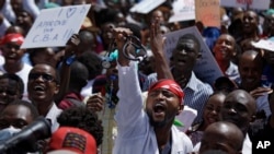 FILE - A doctor holds his stethoscope in the air as he and other medical staff protest the detention of their union leaders, outside an appeal court in Nairobi, Kenya, Feb. 15, 2017. 