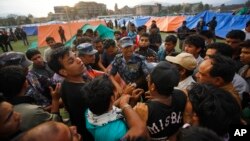 A Nepalese policeman argues with earthquake victims before distributing tents in Kathmandu, Nepal, April 26, 2015. 