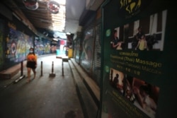 A passerby wearing a face mask passes a closed massage shop in Khao San road, a popular hangout for Thais and tourists in Bangkok, Thailand, April 26, 2021.