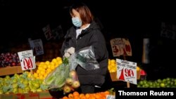 ARCHIVO - Una mujer compra frutas en un mercado al aire libre en Brooklyn, Nueva York.