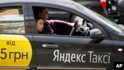 FILE - A woman rides in a Yandex taxi in Kyiv, Ukraine, May 16, 2017. Primarily web-based, Yandex is a Russian technology company specializing in Internet-related services and products.