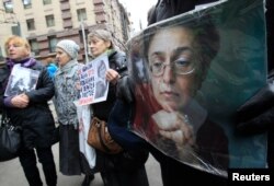FILE - People hold portraits of slain journalist Anna Politkovskaya on the sixth anniversary of her death, next to her block of flats in central Moscow, Oct. 7, 2012.