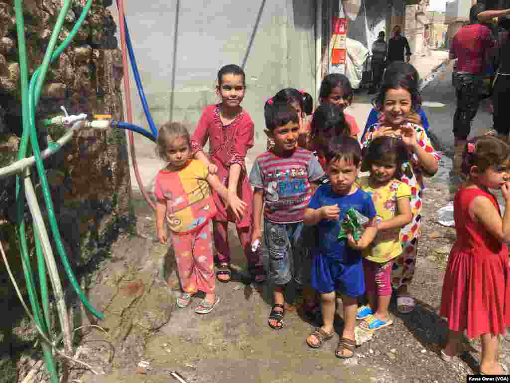 کۆمەڵێک منداڵ لە گەڕەکی موسڵی کۆن لە بەردەم سۆندەیەکی ئاو