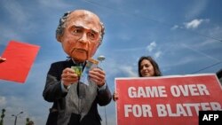 Demonstrators, including one wearing a mask depicting FIFA President Sepp Blatter, protest in front of the Hallenstadium where the 65th FIFA Congress takes place in Zurich, May 29, 2015.