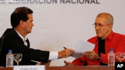 Frank Pearl, left, head of Colombia's peace negotiation team, hands documents to Antonio Garcia, chief negotiator of the National Liberation Army, or ELN, during a signing agreement to start peace talks, in Caracas, Venezuela, March 30, 2016.