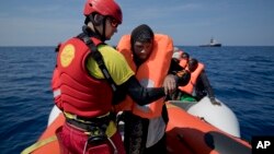 FILE - Proactiva Open Arms lifeguard Ivan Martinez, from Spain, rescues migrants from a rubber boat sailing out of control, in the Mediterranean sea, about 56 miles north of Sabratha, Libya, April 6, 2017. 