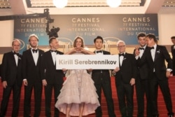 FILE - Holding a sign with the name of the banned director, Kirill Serebrennikov, are president of the Cannes Film Festival Pierre Lescure, producer Ilya Stewart, actors Roman Bilyk, Irina Starshenbaum and Teo Yoo, festival director Thierry Fremaux, actor Charles-Evrard Tchekhoff and cinematographer Vladislav Opelyants at the premiere of the film 'Leto' at the 71st international film festival, Cannes, France, May 9, 2018.