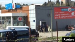 Dalam gambar yang diperoleh dari video yang diunggah di media sosial ini, terlihat polisi tengah berjaga di sekitar lokasi penyanderaan di sebuah supermarket di Trebes, Aude, Perancis, 23 Maret 2018. (Foto:LA VIE A TREBES/via REUTERS)