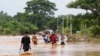 Sejumlah warga lokal berjalan melewati jalan yang tergenang banjir sambil membawa makanan di Naypyitaw, Myanmar, pada 14 September 2024. (Foto: AP/Aung Shine Oo)