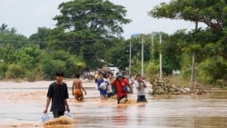 Sejumlah warga lokal berjalan melewati jalan yang tergenang banjir sambil membawa makanan di Naypyitaw, Myanmar, pada 14 September 2024. (Foto: AP/Aung Shine Oo)