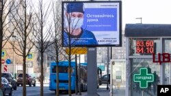 Papan elektronik di jalanan Moskow, Rusia, menampilkan pesan layanan masyarakat bergambar dokter yang mengenakan masker dengan imbauan untuk tetap tinggal di rumah saat pandemi corona di negara itu. (Foto: AP/Alexander Zemlianichenko)