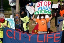 FILE - Protesters display placards while calling for support for tenants and homeowners at risk of eviction during a demonstration on the Boston Common, in Boston, Oct. 11, 2020.