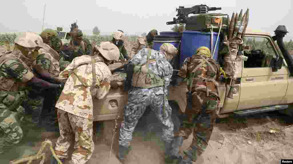 Des soldats tchadiens poussent et tentent de sortir du sable&nbsp; une camionnette de l&#39;armée près de la ligne de front durant la guerre contre le groupe d&#39;insurgés Boko Haram à Gambaru, Nigeria, le 26 février 2015.