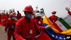 A Venezuelan oil worker holding a small Iranian flag attends a ceremony for the arrival of Iranian oil tanker Fortune at the El Palito refinery near Puerto Cabello, Venezuela, May 25, 2020. 