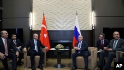 Russian President Vladimir Putin, center right, and Turkish President Recep Tayyip Erdogan , center left, speak during their meeting in the Bocharov Ruchei residence in the Black Sea resort of Sochi, Russia, Oct. 22, 2019.