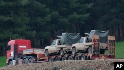 A truck, part of a convoy, carrying military pickup trucks with machine guns attached is seen on the outskirts of the village of Sugedigi, Turkey, Jan. 21, 2018. Several military trucks carrying tanks and other armored vehicles crossed into Syria late Saturday, in anticipation of a ground offensive into a Syrian Kurdish enclave. 