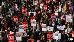 Manifestantes seguram cartazes enquanto se reúnem em Trafalgar Square apelando ao fim da violência masculina contra as mulheres, em Londres, a 8 de março de 2025, para assinalar o Dia Internacional das Mulheres.