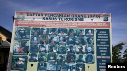 FILE - A police billboard shows individuals — including Santoso, top left — wanted in connection with terrorism cases, in Poso, Central Sulawesi province, Indonesia, Dec. 19, 2015. Development in the province is part of officials' efforts to dissuade would-be terrorists.